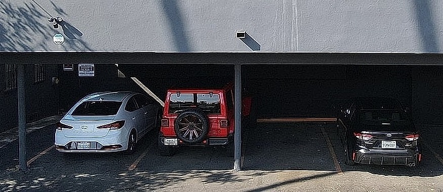 Two-story building with cars in parking area.