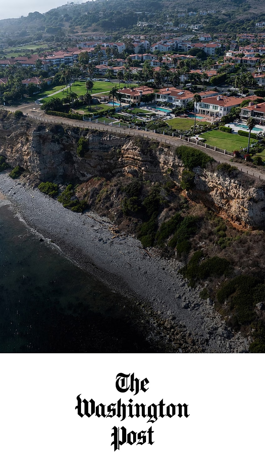 Coastal view with residential buildings and cliffs.