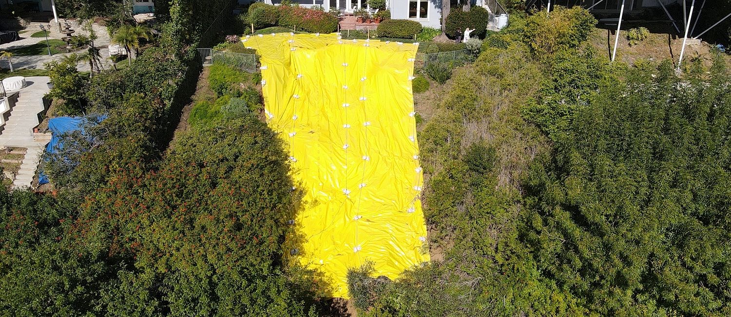 Yellow tarp covering a hillside landscape.