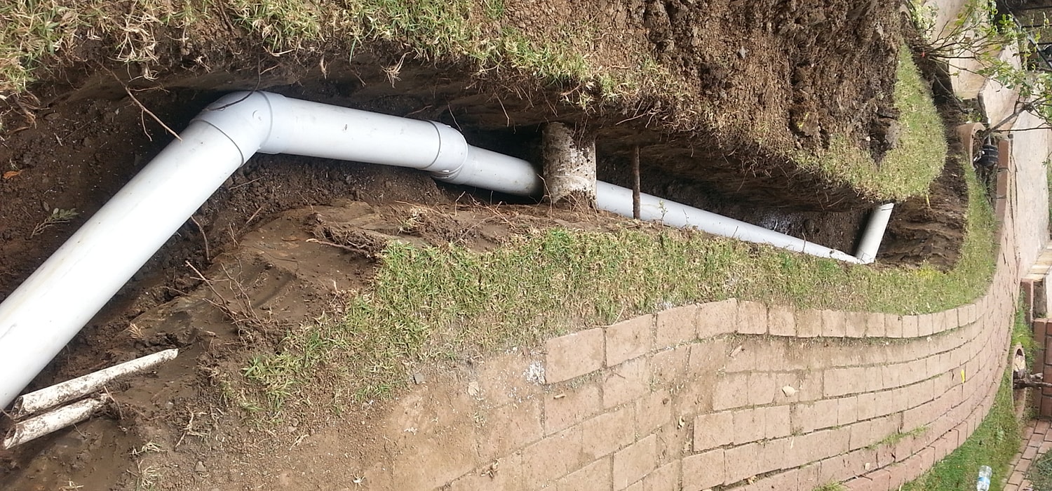 Underground PVC piping installation in grassy area.