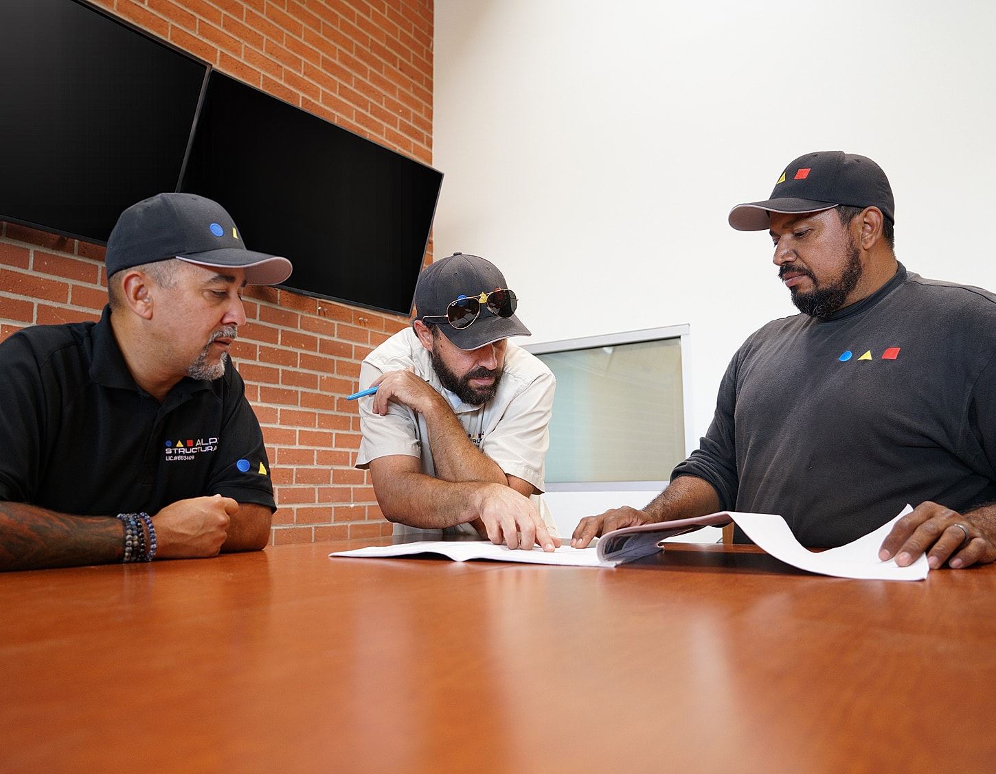 Three men discussing documents in office setting.