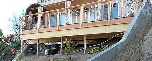 Elevated house with wooden deck on slope.