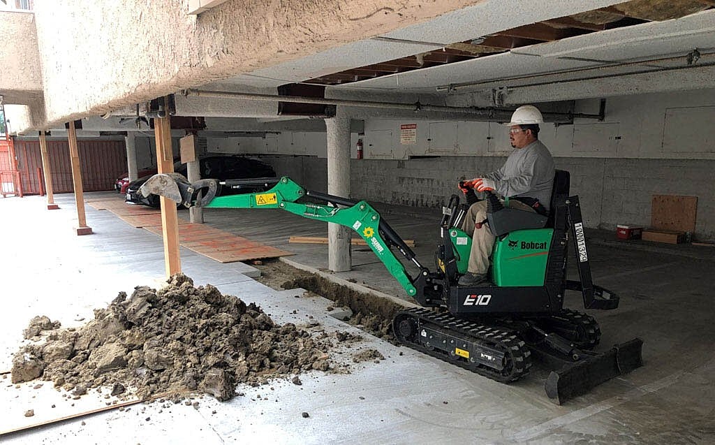 Mini excavator working in a parking garage.