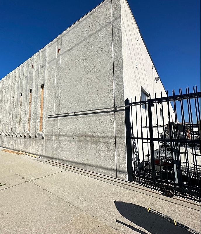 Concrete building corner with gated entrance.