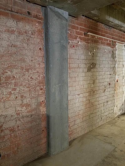 Concrete pillar against a brick wall interior.