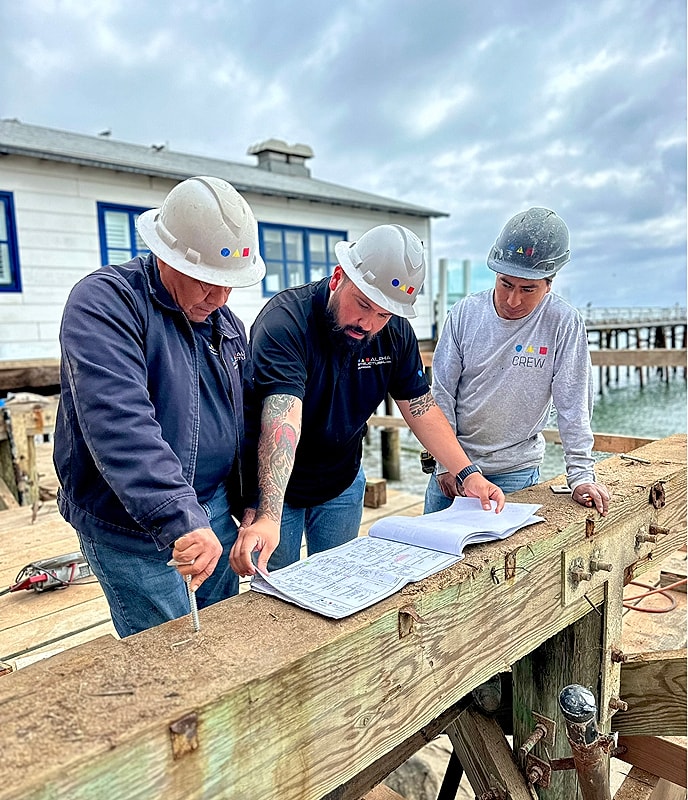 Construction workers reviewing project plans outdoors.