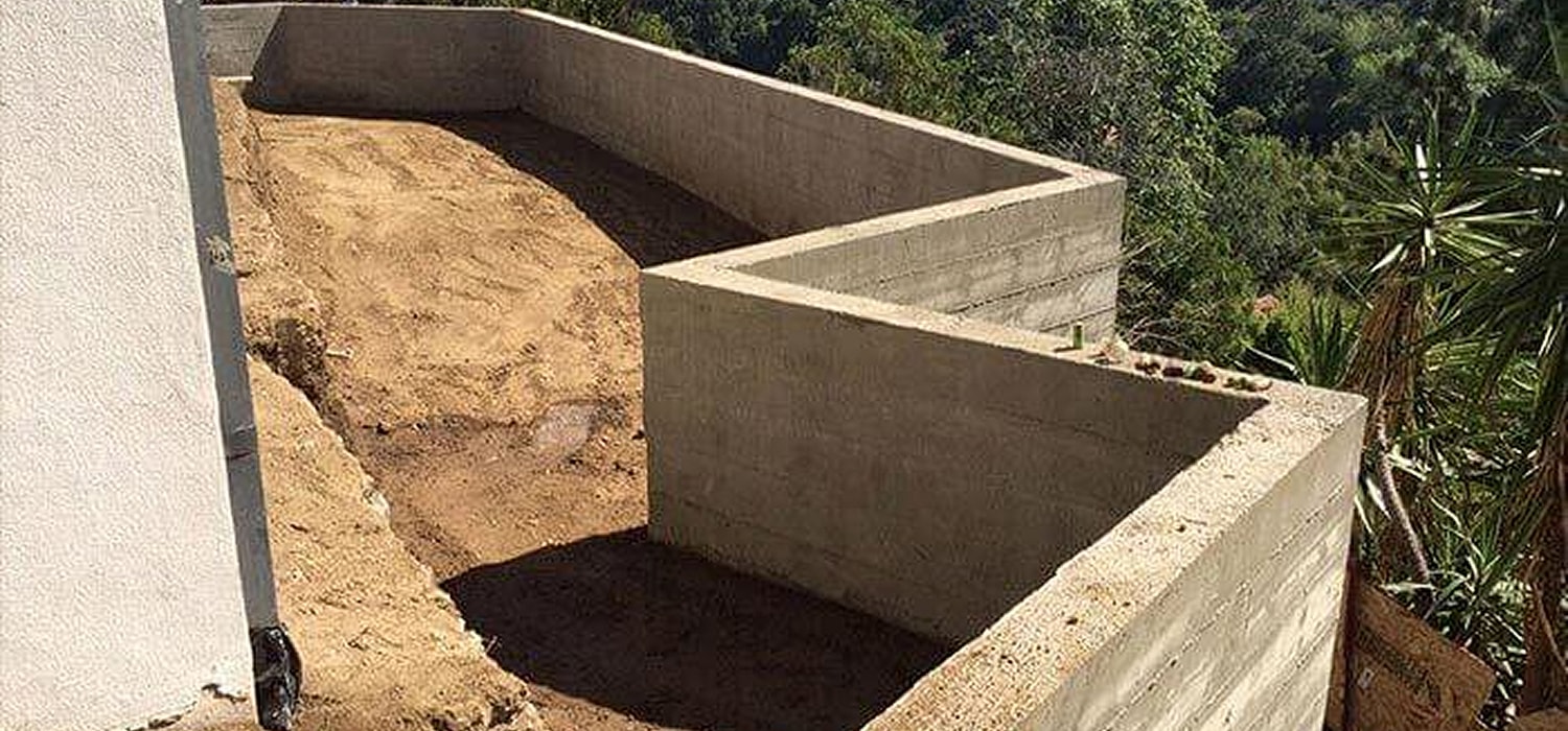 Concrete structure with dirt area and greenery.