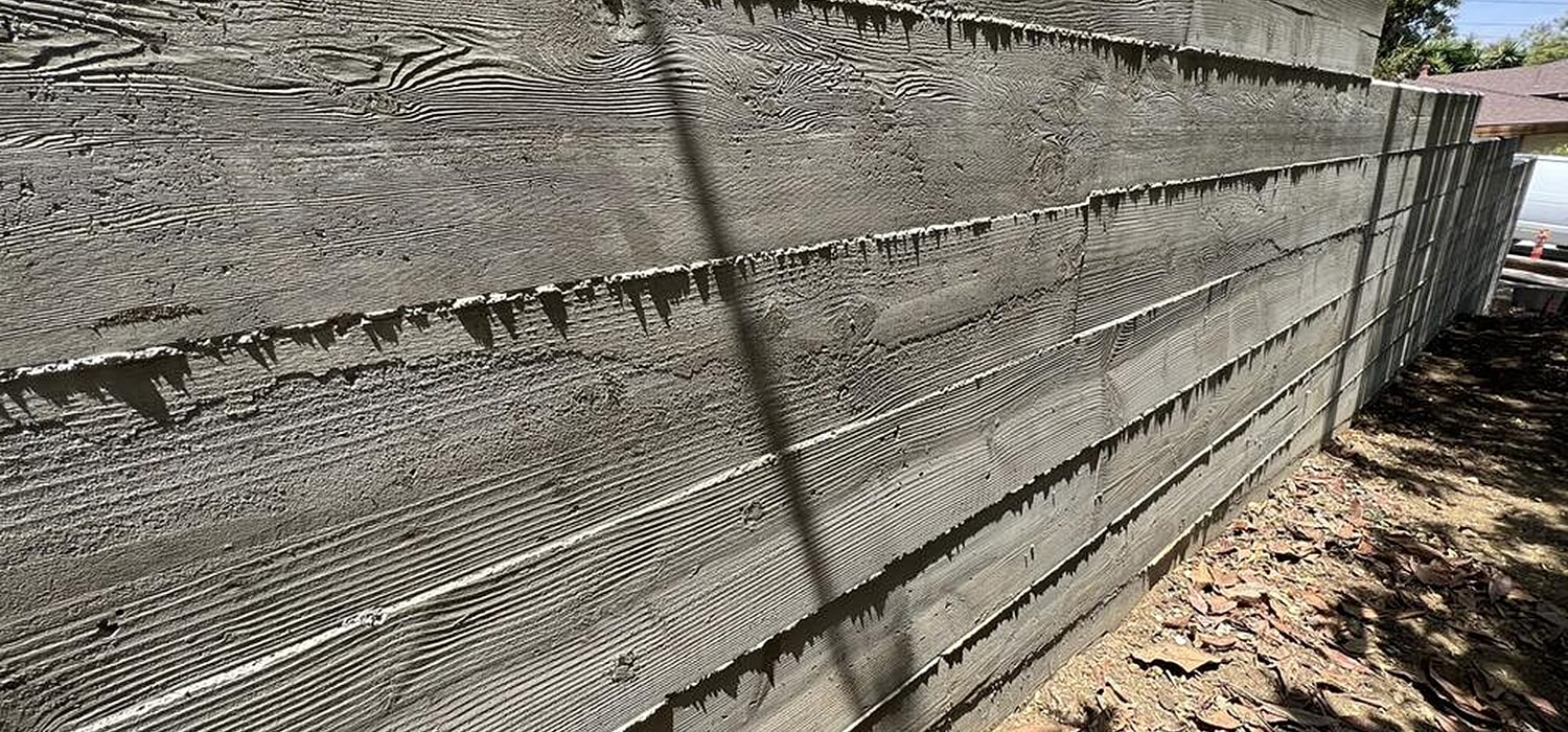 Textured gray wooden fence in sunlight.