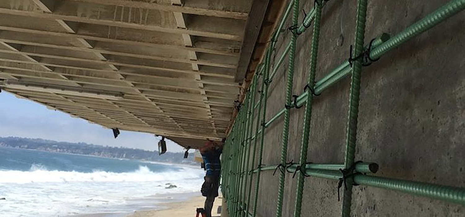 Worker repairing coastal structure under construction.