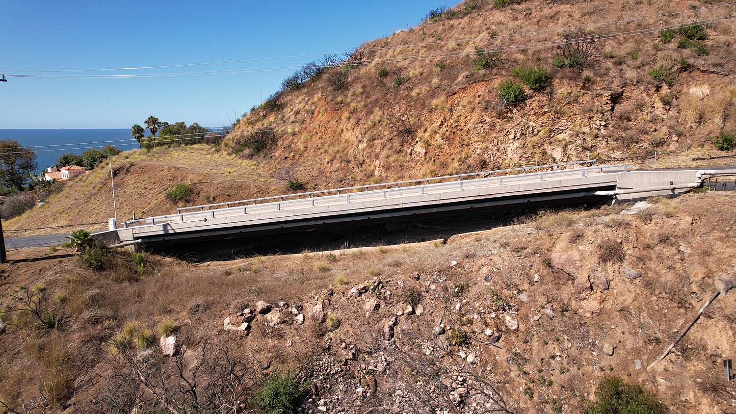 Bridge overlooking a coastal landscape and hillside.