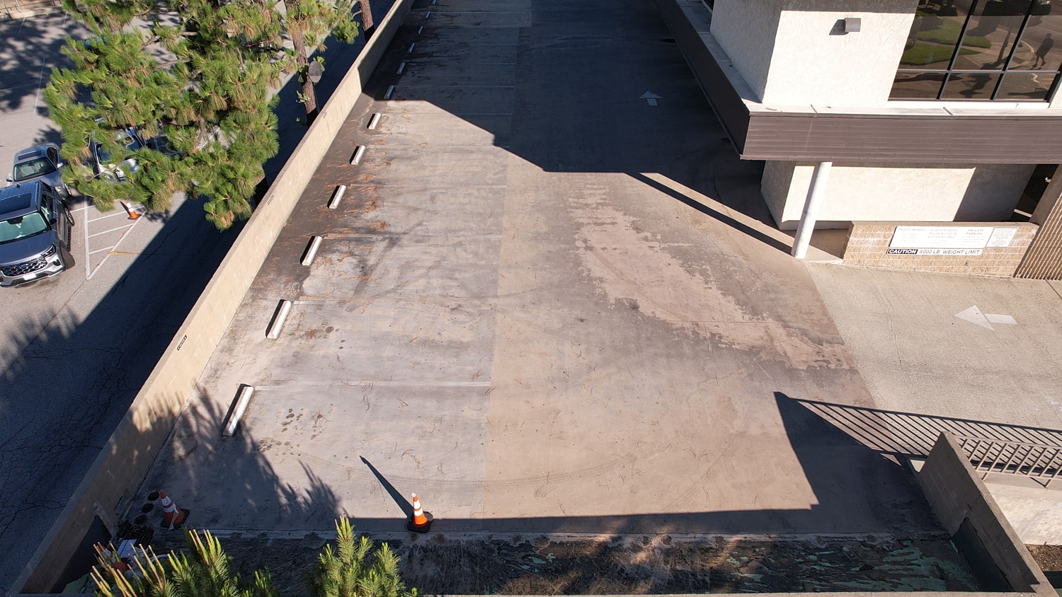 Empty parking lot with adjacent building and trees.