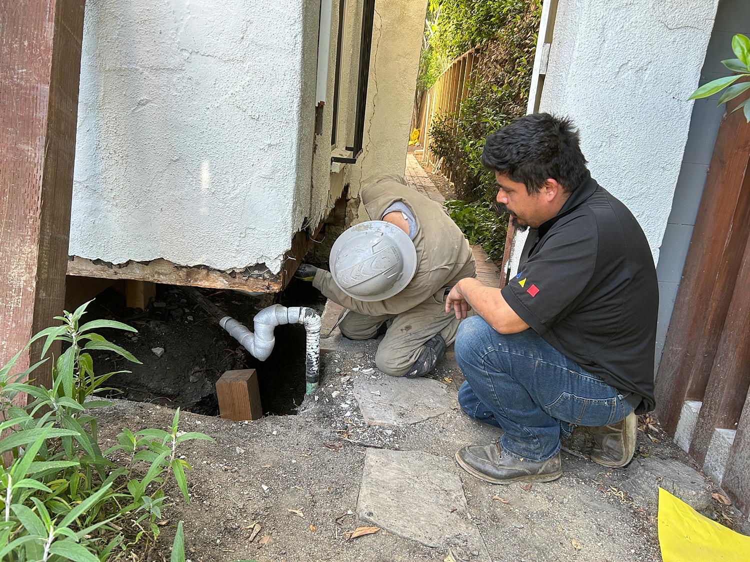 Inspecting plumbing under a damaged building foundation.