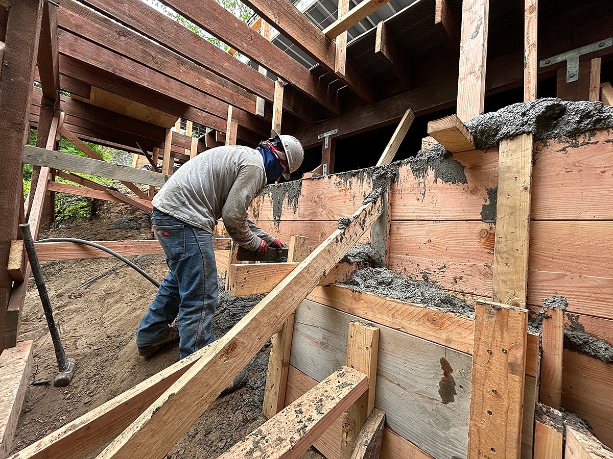 Construction worker pouring concrete at building site.