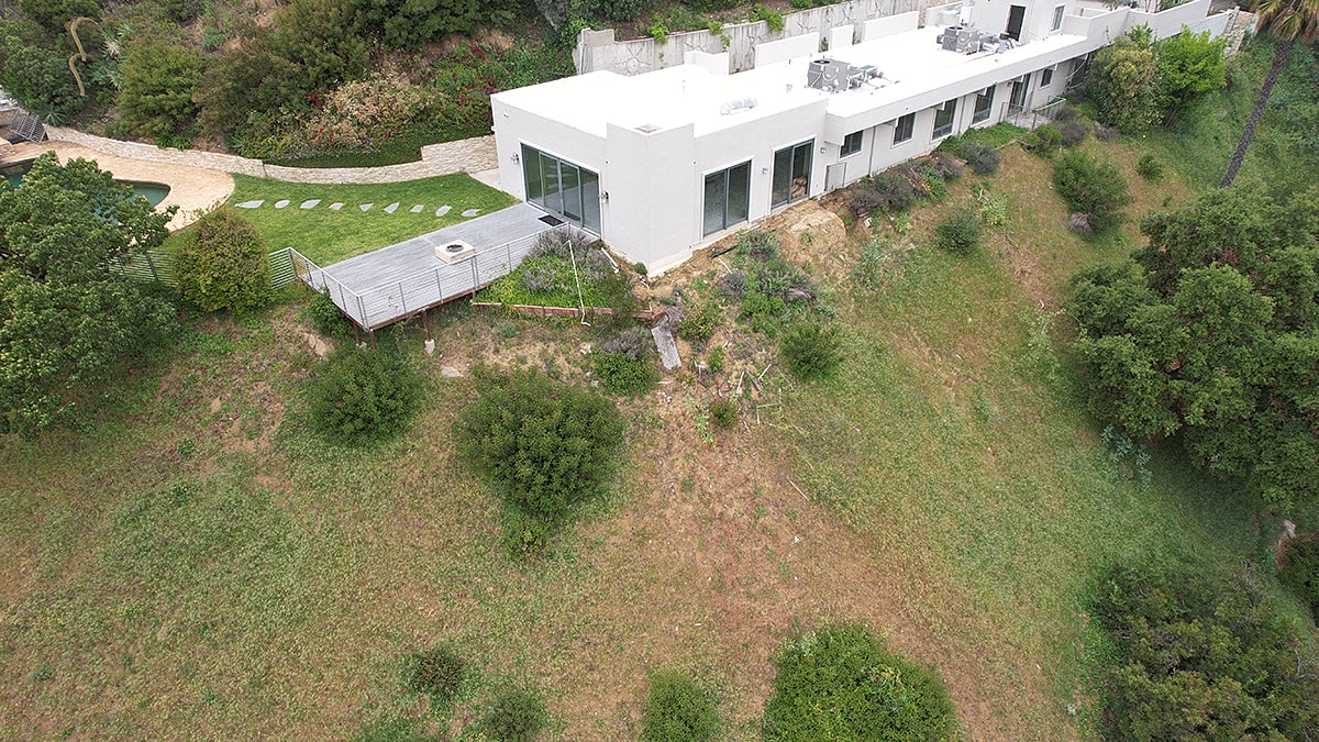 Modern house on a hillside with landscaped yard.