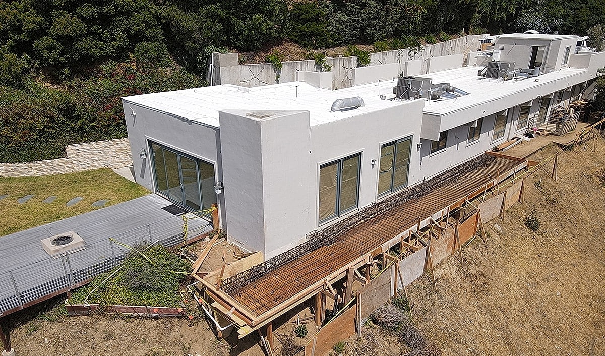 Modern house under construction on a hillside.