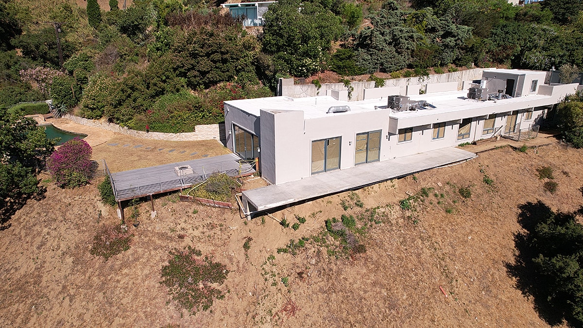Modern house on hillside with lush greenery.