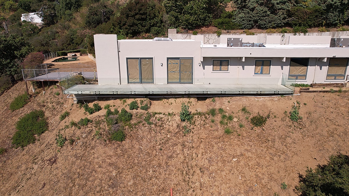 Modern house with glass balcony on hillside.