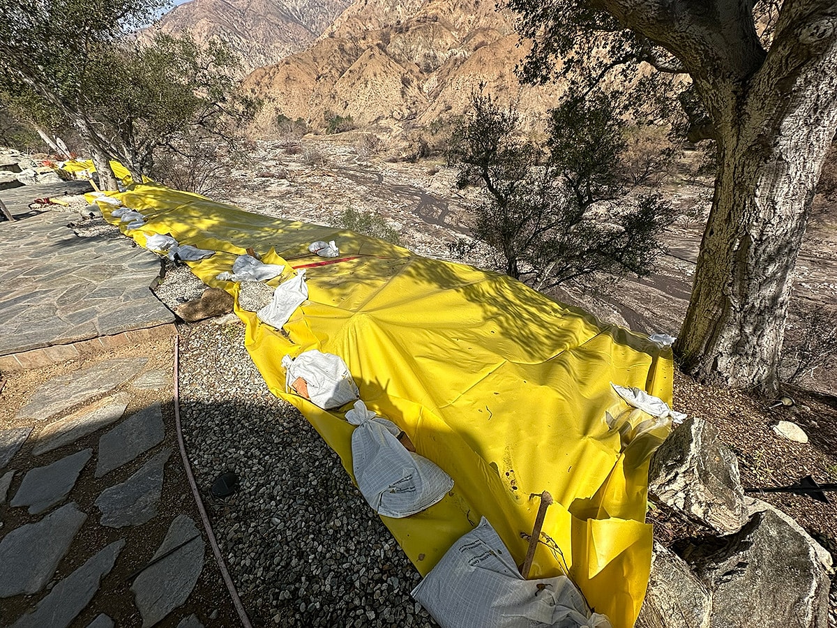 Yellow tarp on rocky landscape near riverbank.