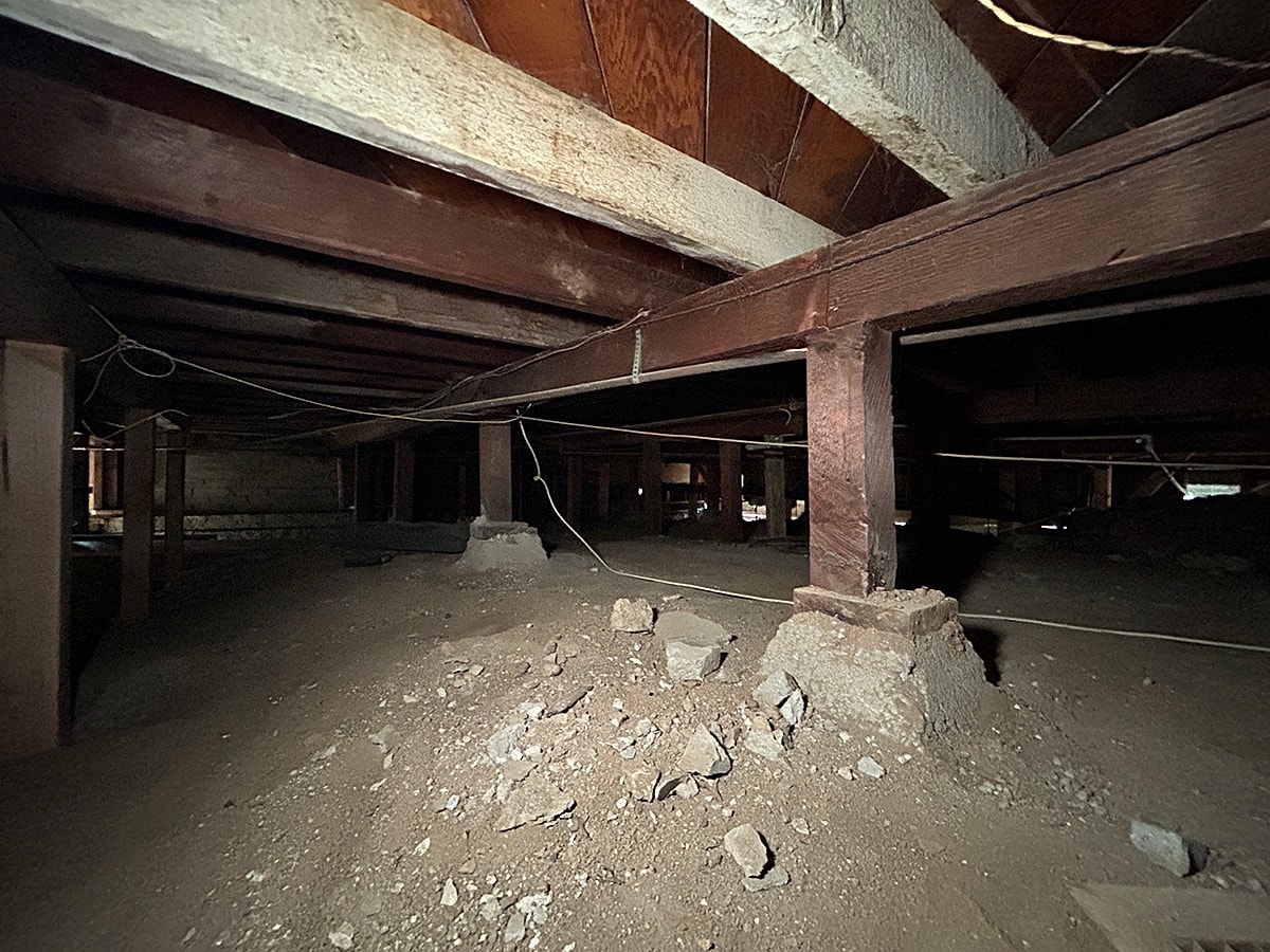 Dimly lit basement with wooden beams and debris.