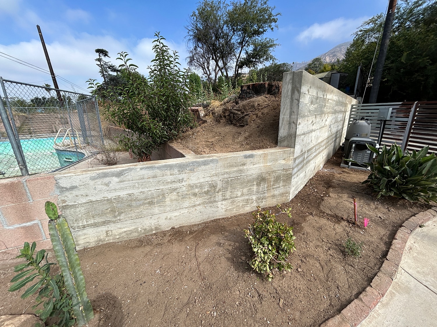 Concrete wall in backyard near swimming pool.