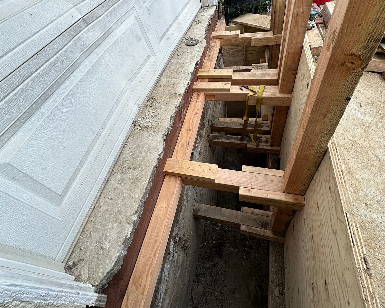 Construction site with wooden supports and trench.